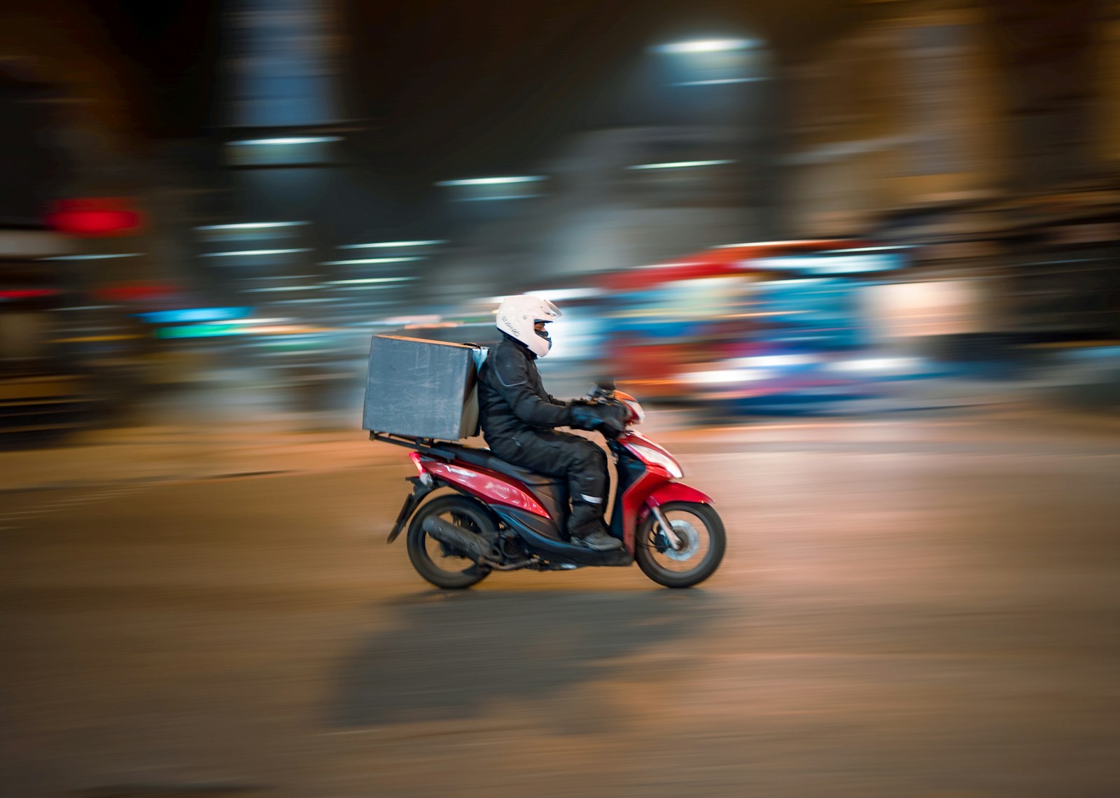 A motorbike dispatch rider moving through the city at night
